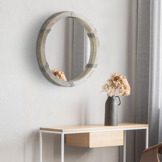Round mirror on a wall above a wooden console table with a vase of flowers.