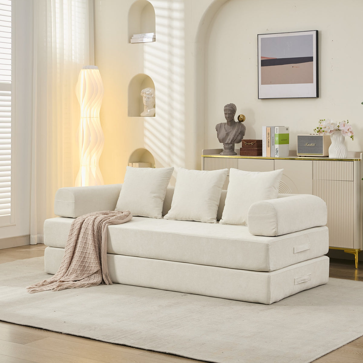 Beige sofa bed in a modern living room setting with decor elements.